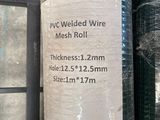 a roll of wire mesh on the ground next to a roll of plastic