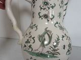 a white vase with green and white designs on it