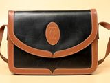une image représentant un sac à main noir et marron sur fond beige