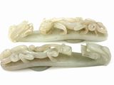two pieces of carved jade hair clips on a white surface