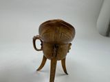 a small bronze cup on a stand on a white surface