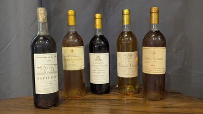 six bottles of wine are lined up on a wooden table