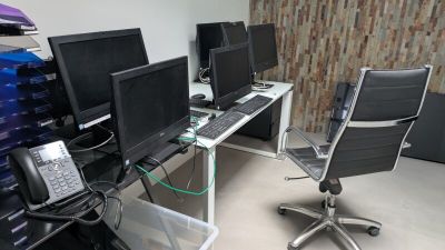 trois ordinateurs posés sur le bureau dans la pièce