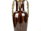 a brown vase with a gold handle on a white background