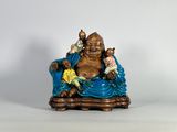 une statue représentant un Bouddha souriant assis sur une chaise