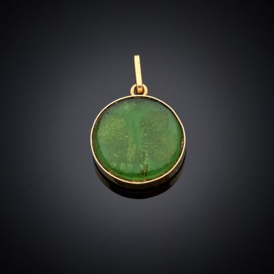 un pendentif en or orné d'une pierre verte au centre