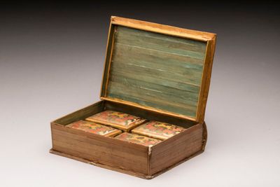 une vieille boîte en bois contenant quatre cartes, posée sur une surface blanche