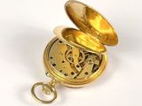 a small gold pocket watch with a key in it