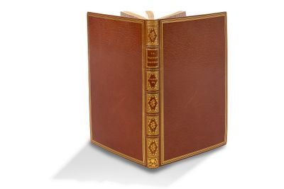 un vieux livre à la couverture dorée posé sur une surface blanche