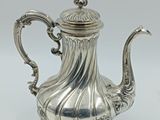 une théière ancienne en argent avec une anse, sur fond blanc