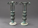 pair of antique bronze vases on pedestals against a gray background