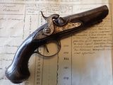 un vieux pistolet posé sur une feuille de papier, sur une table