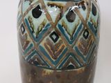 a brown and blue vase sitting on a white surface