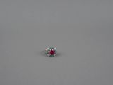 une bague ornée d'un seul rubis et de diamants, posée sur une surface grise