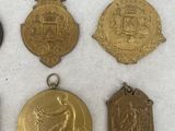 six medals of various shapes and sizes on a white surface