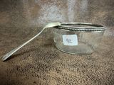 a silver spoon sitting next to a glass jar with a spoon in it