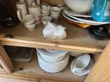 many plates and cups stacked on a shelf in a cabinet