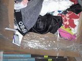 a cardboard box filled with clothes and clothes on the floor