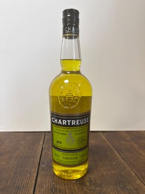 une bouteille de whisky à la Chartreuse posée sur une table en bois