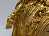 a gold clock with a statue of a woman sitting on top of it