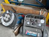 un petit compresseur d'air posé par terre à côté d'un tas d'outils