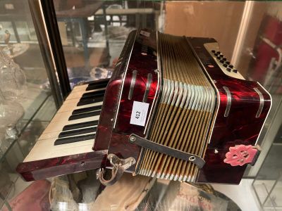 a red and white accordion on display in a glass case