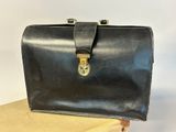 a black leather briefcase sitting on top of a wooden table