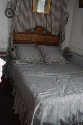 un lit recouvert d'une couette argentée, dans une chambre aux murs rayés