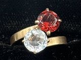 a red and white diamond ring sitting on a black velvet box
