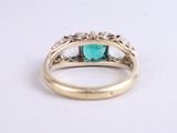 a close up of a gold ring with an emerald stone and diamonds