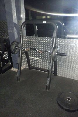 une photo d'une salle de sport avec une barre et des haltères