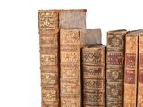 several old books are stacked on top of each other on a white surface