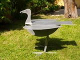 a metal bird that is sitting in the grass