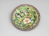 une assiette verte sur laquelle sont peints des fleurs et des oiseaux
