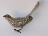 un oiseau argenté posé sur une surface blanche