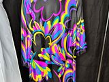a colorful shirt hanging on a rack next to a coat rack