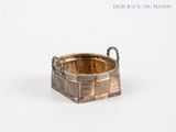 a small metal basket with a handle on a white surface