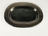 une assiette noire posée sur une table blanche, avec une poignée en argent