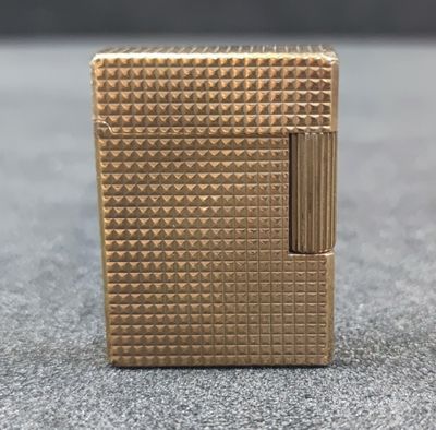 a close up of a gold lighter sitting on top of a table