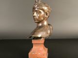 bronze bust of a young boy on a wooden base on a black surface