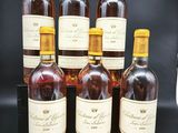 six bouteilles de vin sont alignées sur une table