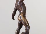 bronze statue of a man holding a football on a marble base
