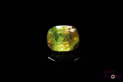 un gros plan d'un anneau jaune et vert sur une surface noire