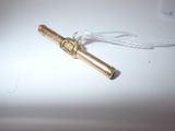 a small gold pipe on a white table with a string
