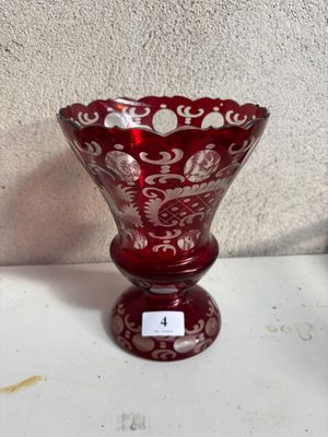 un vase en verre rouge posé sur une table, avec une étiquette dessus