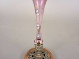 a pink glass vase sitting on top of a wooden base