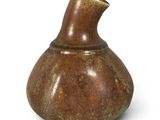 un vase brun posé sur une surface blanche