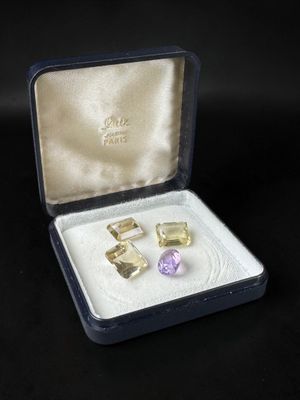 pair of yellow and purple gems in a box on a black surface