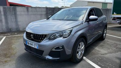 La voiture grise est garée sur le parking à côté de l'immeuble.