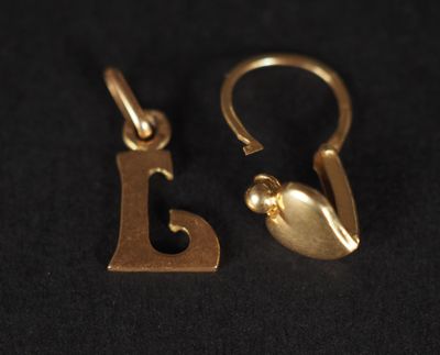 un gros plan sur une paire de boucles d'oreilles en or posées sur une surface noire